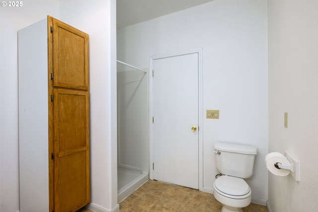 full bath featuring baseboards, toilet, and a shower stall