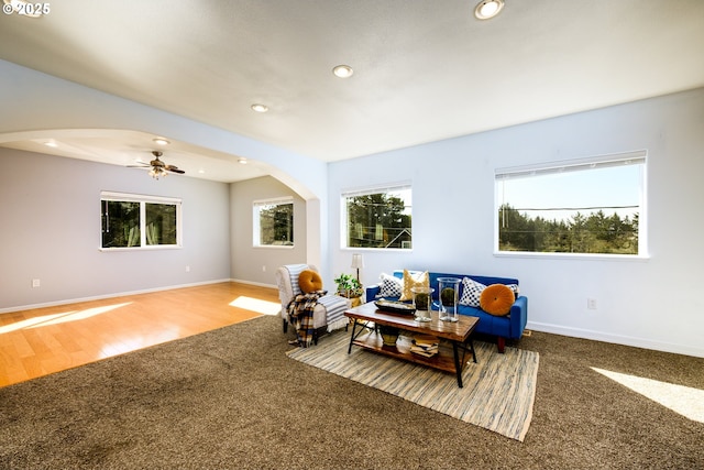living area with arched walkways, baseboards, recessed lighting, and plenty of natural light