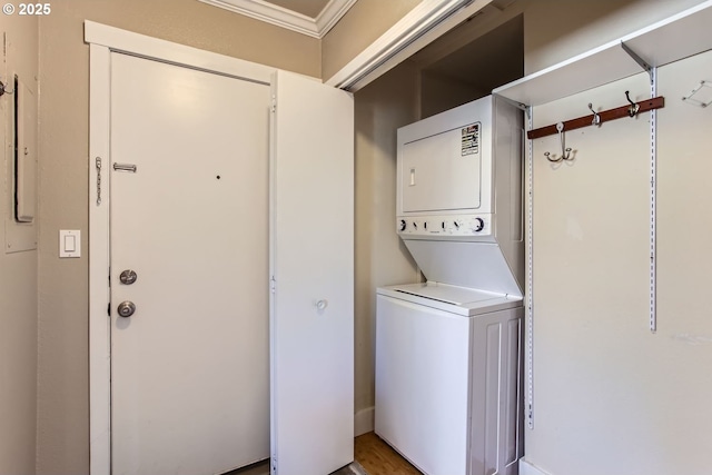 clothes washing area featuring crown molding and stacked washing maching and dryer