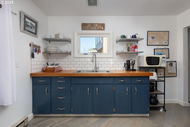 kitchen with sink, decorative backsplash, blue cabinetry, and baseboard heating