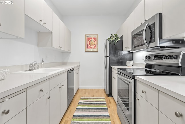 618 NW 12th Ave, Portland, OR 97209 - kitchen featuring appliances with stainless steel finishes, light wood-style flooring, light countertops, and white cabinetry