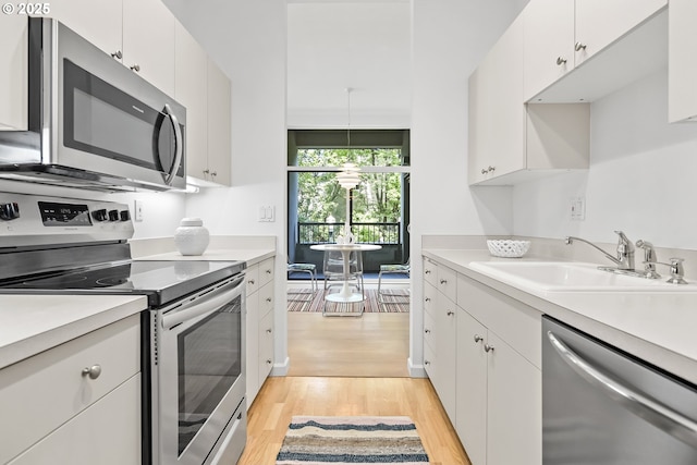 618 NW 12th Ave, Portland, OR 97209 - kitchen with stainless steel appliances, light wood-style flooring, light countertops, and white cabinets