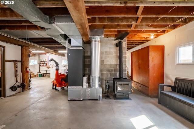 9602 Harlan Rd, Eddyville, OR 97343 - basement featuring a wood stove, heating unit, and concrete block wall