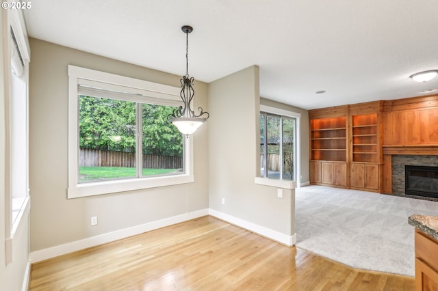12955 SW Oxalis Ter, Portland, OR 97223 - unfurnished dining area with light wood-type flooring, a glass covered fireplace, and built in shelves
