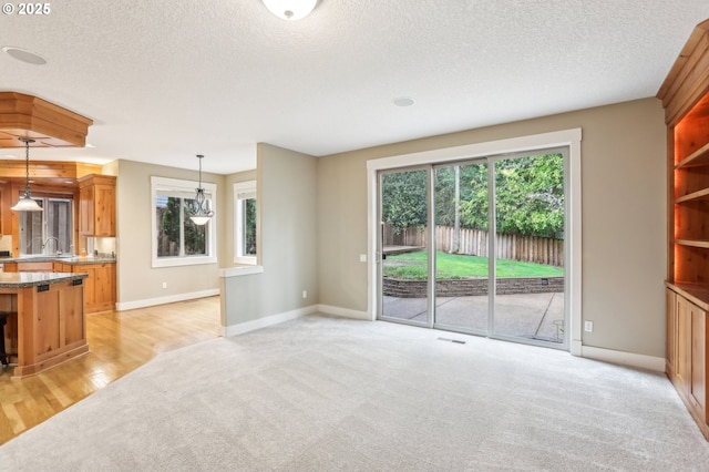 12955 SW Oxalis Ter, Portland, OR 97223 - unfurnished living room with light colored carpet, a textured ceiling, and light wood-style flooring