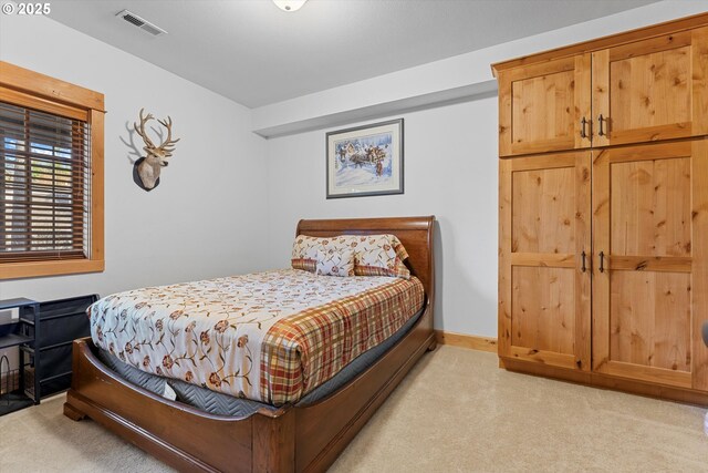 bedroom with visible vents, baseboards, and light carpet