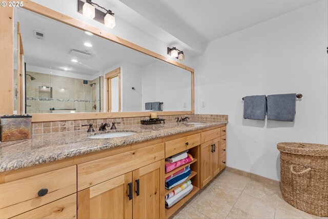 full bath featuring a sink, a shower stall, backsplash, and double vanity