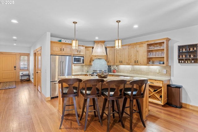 kitchen featuring light brown cabinetry, appliances with stainless steel finishes, baseboards, light wood-type flooring, and custom exhaust hood