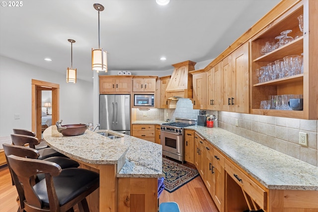 kitchen with a sink, stainless steel appliances, decorative backsplash, light wood-type flooring, and custom exhaust hood