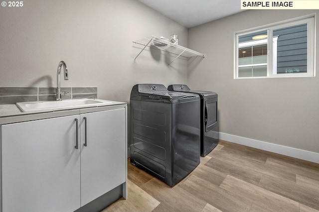 laundry area with cabinets, separate washer and dryer, light hardwood / wood-style floors, and sink