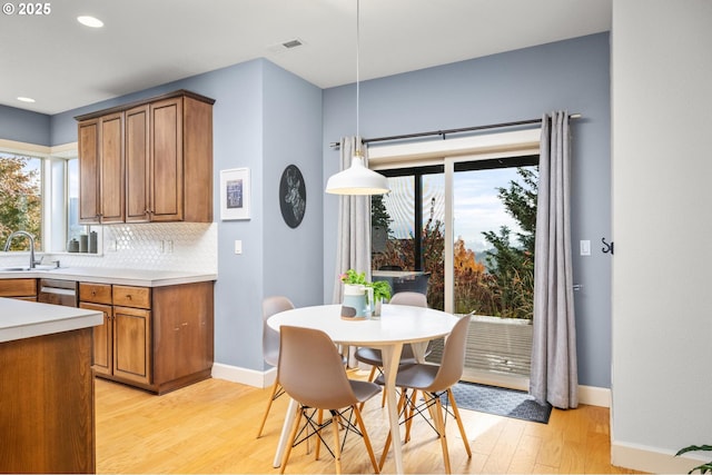 kitchen featuring decorative light fixtures, light countertops, visible vents, brown cabinetry, and a sink