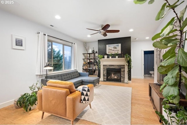 living room featuring recessed lighting, a fireplace, light wood-style flooring, and baseboards