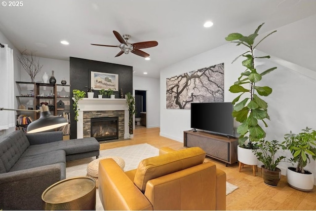 living room with light wood-type flooring, a stone fireplace, and recessed lighting