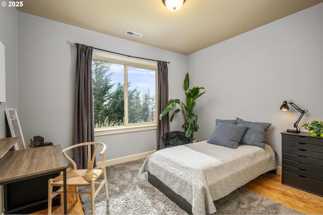 bedroom featuring visible vents, baseboards, and wood finished floors