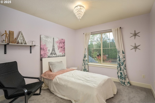 bedroom with light carpet, a textured ceiling, and baseboards