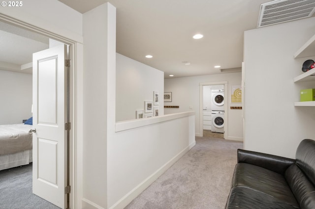 corridor with recessed lighting, light colored carpet, visible vents, stacked washer / dryer, and baseboards