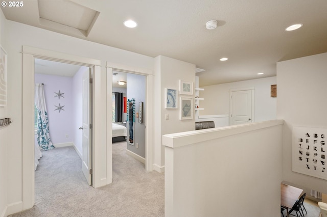 hallway featuring recessed lighting, baseboards, light carpet, and an upstairs landing