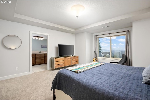 bedroom featuring ensuite bathroom, light colored carpet, visible vents, baseboards, and a raised ceiling