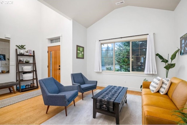 living room with high vaulted ceiling, wood finished floors, visible vents, and baseboards