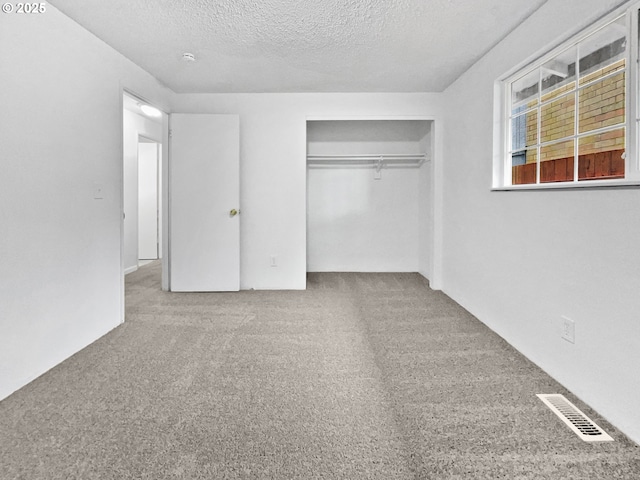 unfurnished bedroom featuring visible vents, carpet, a closet, and a textured ceiling