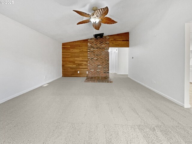 unfurnished living room featuring baseboards, ceiling fan, wood walls, vaulted ceiling, and carpet flooring