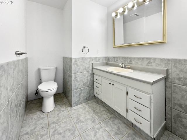 157 SE 205th Dr, Gresham, OR 97030 - half bathroom featuring tile walls, wainscoting, toilet, vanity, and tile patterned flooring