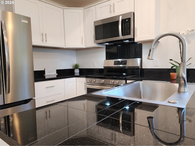 kitchen featuring dark stone countertops, white cabinetry, and stainless steel appliances