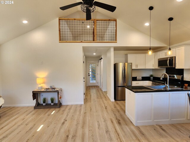 kitchen with a sink, dark countertops, appliances with stainless steel finishes, a ceiling fan, and high vaulted ceiling