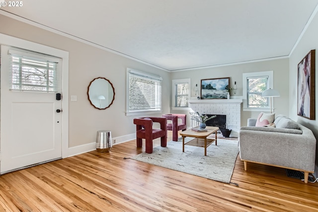 living room featuring a healthy amount of sunlight, light wood-style flooring, a fireplace, and ornamental molding