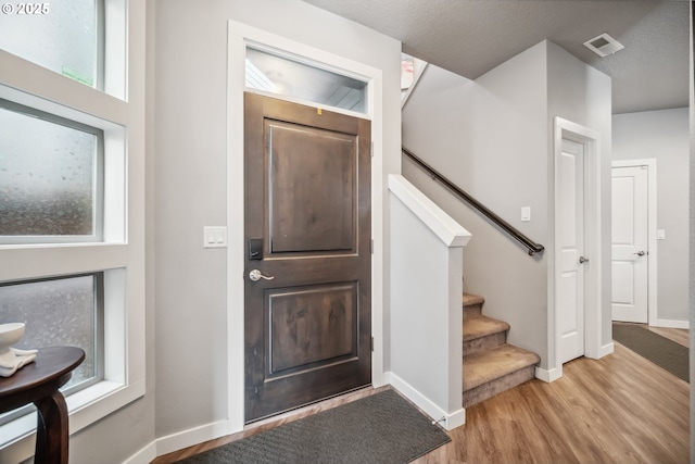 foyer entrance with light hardwood / wood-style floors and a textured ceiling