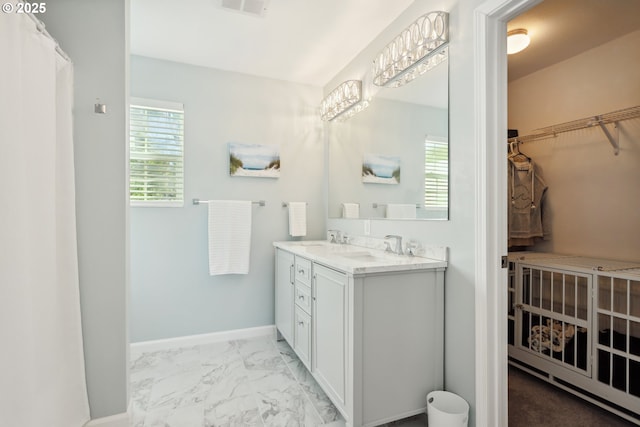 315 W 13th St, The Dalles, OR 97058 - bathroom featuring double vanity, marble look tiles, a walk in closet, and baseboards