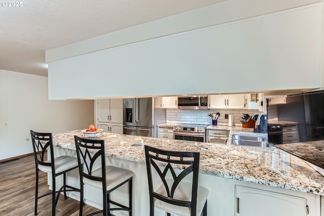 1473 N Locust St, Canby, OR 97013 - kitchen with stainless steel appliances, dark wood finished floors, backsplash, a peninsula, and a kitchen bar