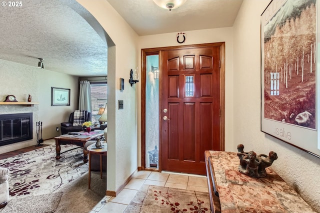1473 N Locust St, Canby, OR 97013 - entryway featuring arched walkways, a textured ceiling, a fireplace, light tile patterned floors, and a textured wall