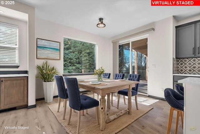 dining room featuring plenty of natural light, light wood-style floors, and baseboards