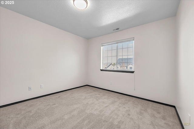 carpeted empty room featuring baseboards, visible vents, and a textured ceiling