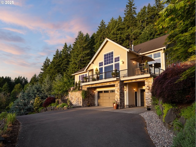 10448 SE 147th Ave, Happy Valley, OR 97086 - view of front of home featuring stone siding, a balcony, driveway, and a garage