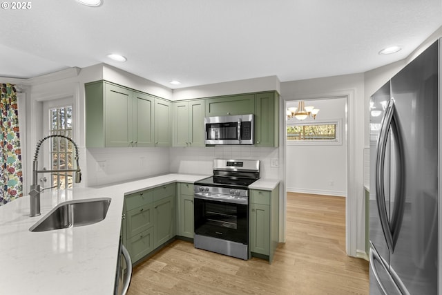 kitchen with stainless steel appliances, green cabinets, sink, and backsplash