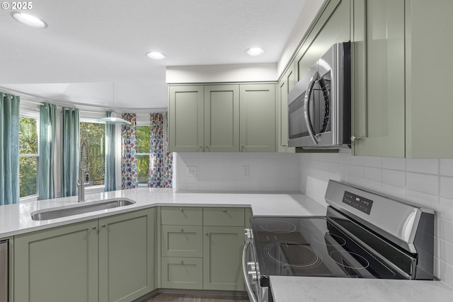 kitchen featuring appliances with stainless steel finishes, decorative backsplash, sink, and green cabinets