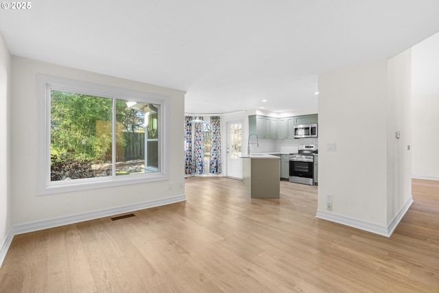 unfurnished living room with sink and light hardwood / wood-style flooring