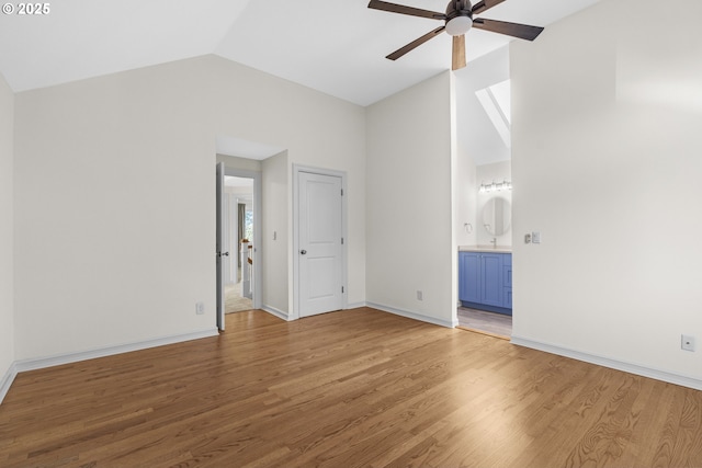 unfurnished bedroom featuring lofted ceiling, ensuite bath, ceiling fan, and hardwood / wood-style floors