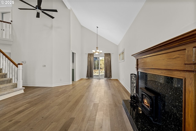 unfurnished living room featuring hardwood / wood-style floors, a towering ceiling, and ceiling fan with notable chandelier