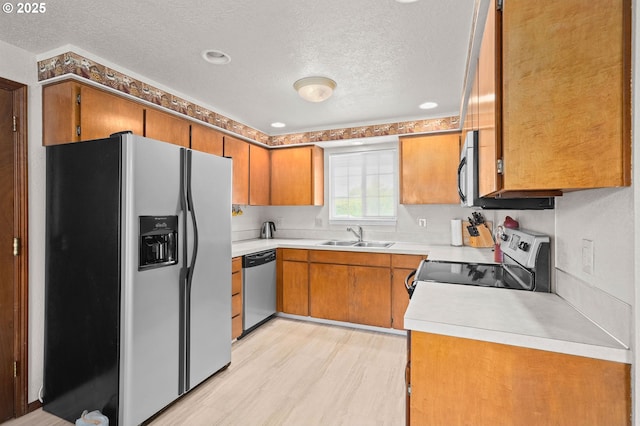 4775 Sienna Dr NE, Salem, OR 97301 - kitchen with stainless steel appliances, a textured ceiling, brown cabinets, light countertops, and light wood-style flooring
