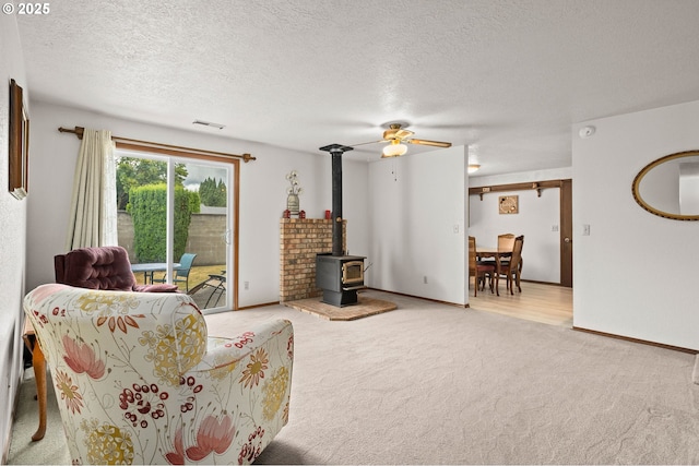 4775 Sienna Dr NE, Salem, OR 97301 - living room with a wood stove, carpet floors, ceiling fan, and a textured ceiling