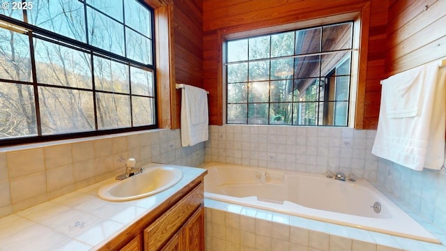 bathroom featuring tiled tub and vanity