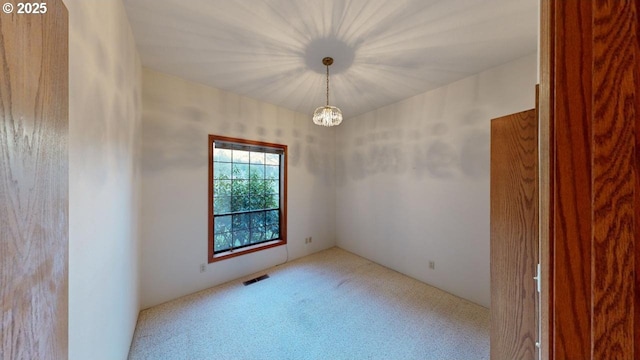 unfurnished room with light carpet and a notable chandelier