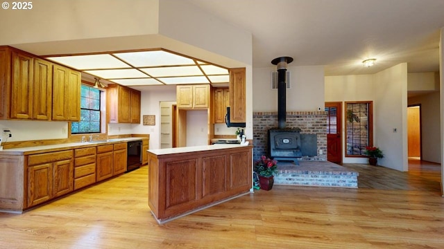 kitchen with dishwasher, kitchen peninsula, light hardwood / wood-style flooring, and a wood stove