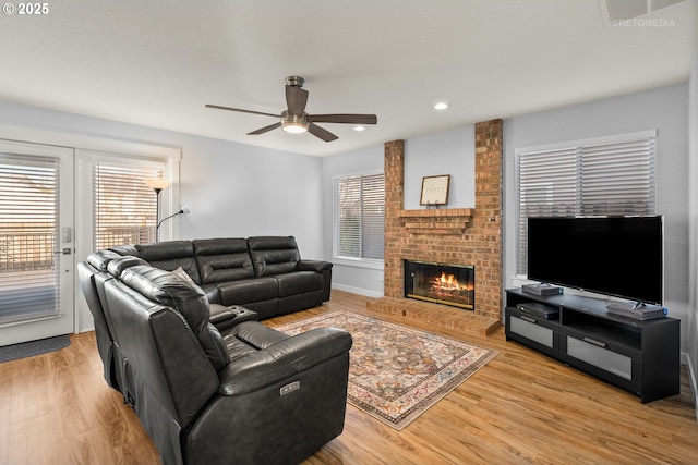 living area featuring light wood finished floors, a brick fireplace, recessed lighting, and a healthy amount of sunlight