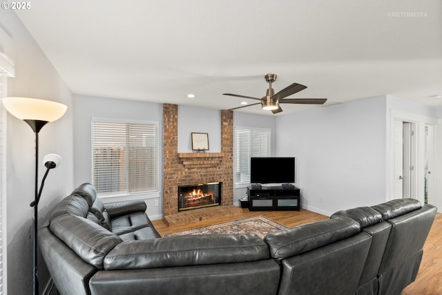 living area featuring recessed lighting, a ceiling fan, a brick fireplace, wood finished floors, and baseboards