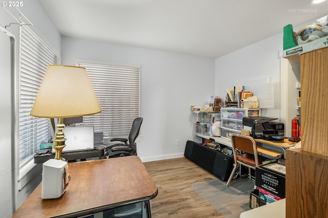 office space with baseboards, wood finished floors, and a healthy amount of sunlight