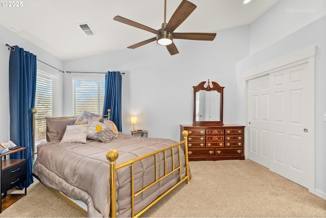 carpeted bedroom featuring a closet, visible vents, vaulted ceiling, and ceiling fan